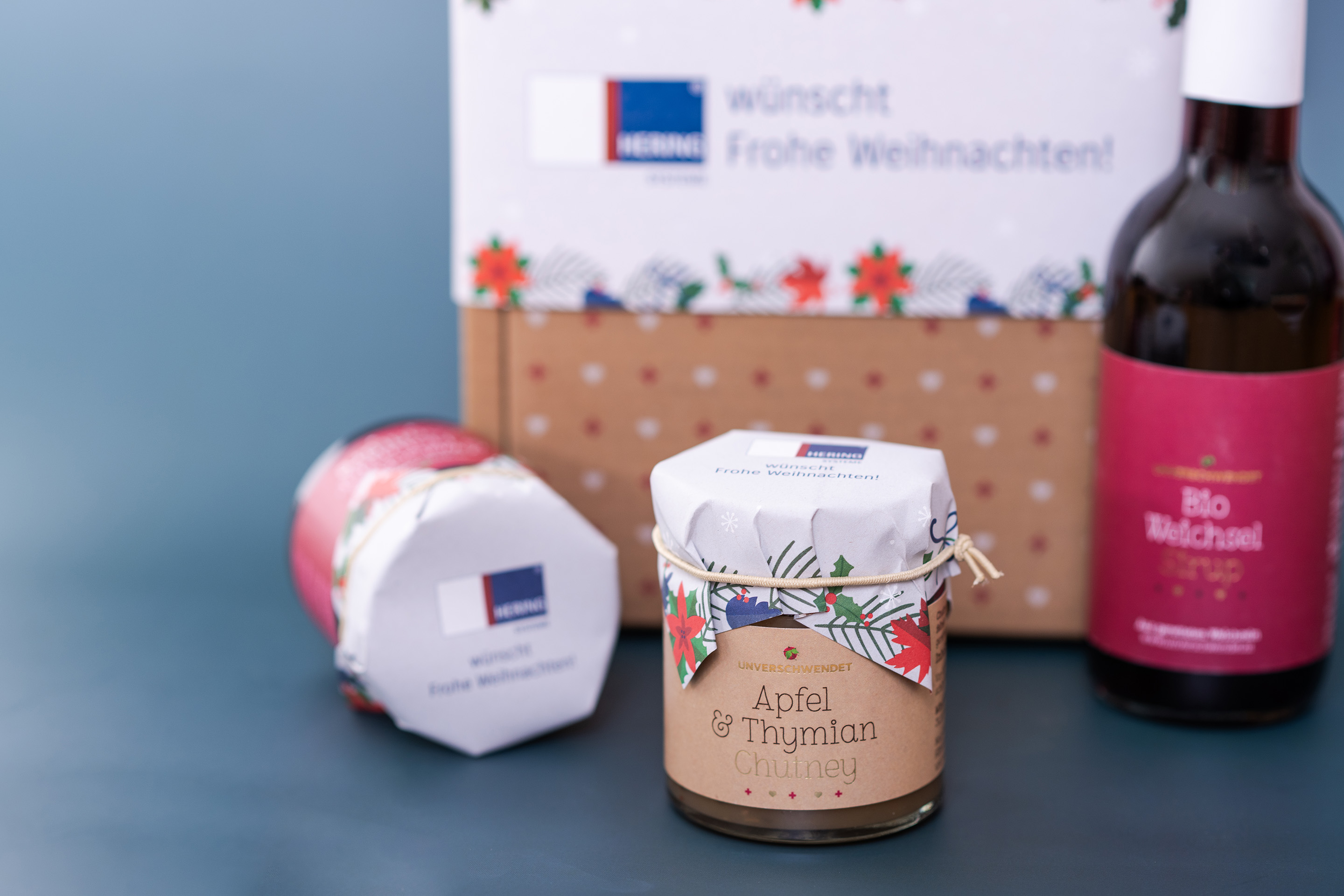 Apfel-Thymian Chutney im Glas mit weiteren Unverschwendet Produkten im Hintergrund (alles im Weihnachtsdesign) Apfel-Thymian Chutney im Glas mit weiteren Unverschwendet Produkten im Hintergrund