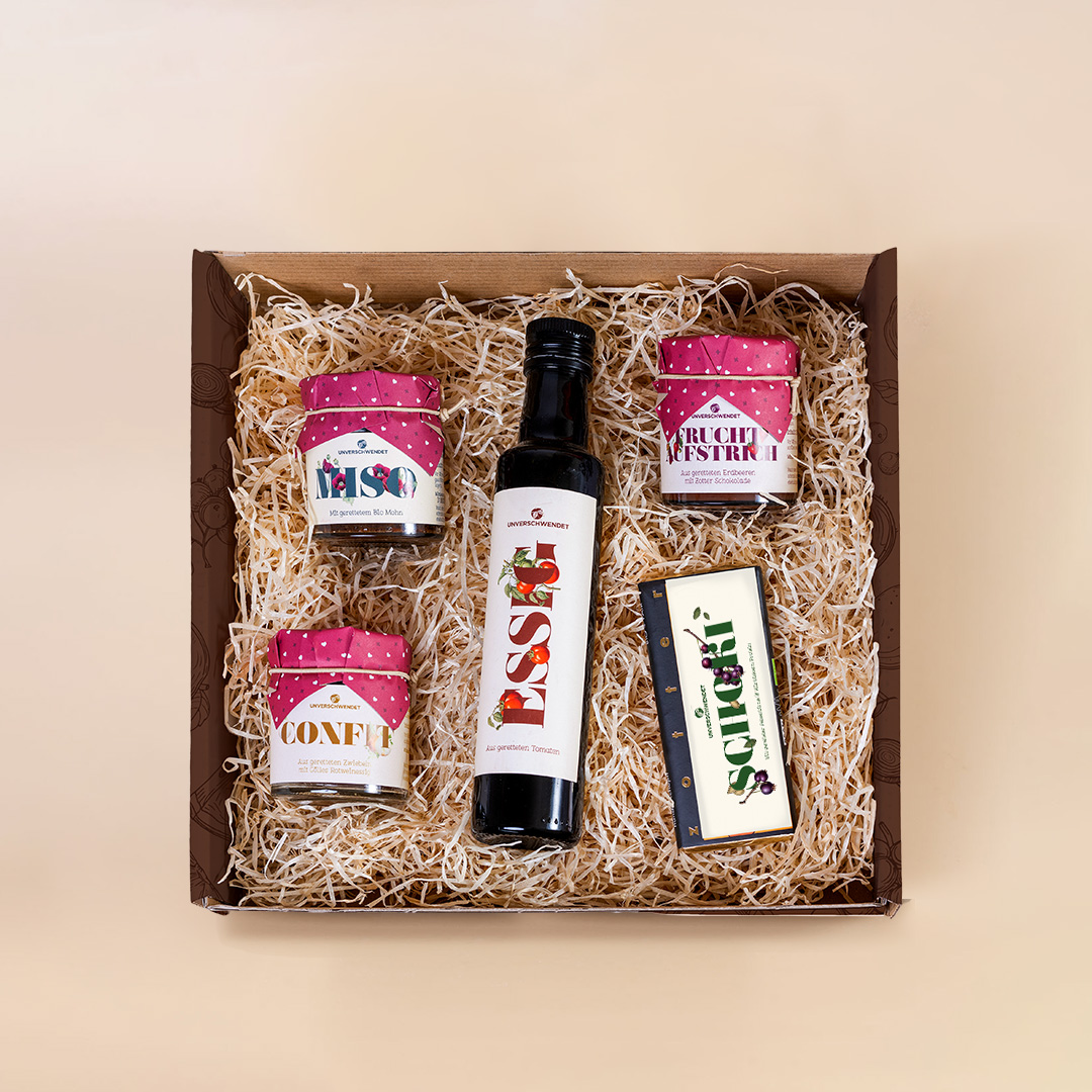 Geschenkbox mit Tomatenessig, Schokolade und Feinkost-Gläschen (von oben fotografiert) Geschenkbox mit Tomatenessig, Schokolade und Feinkost-Gläschen