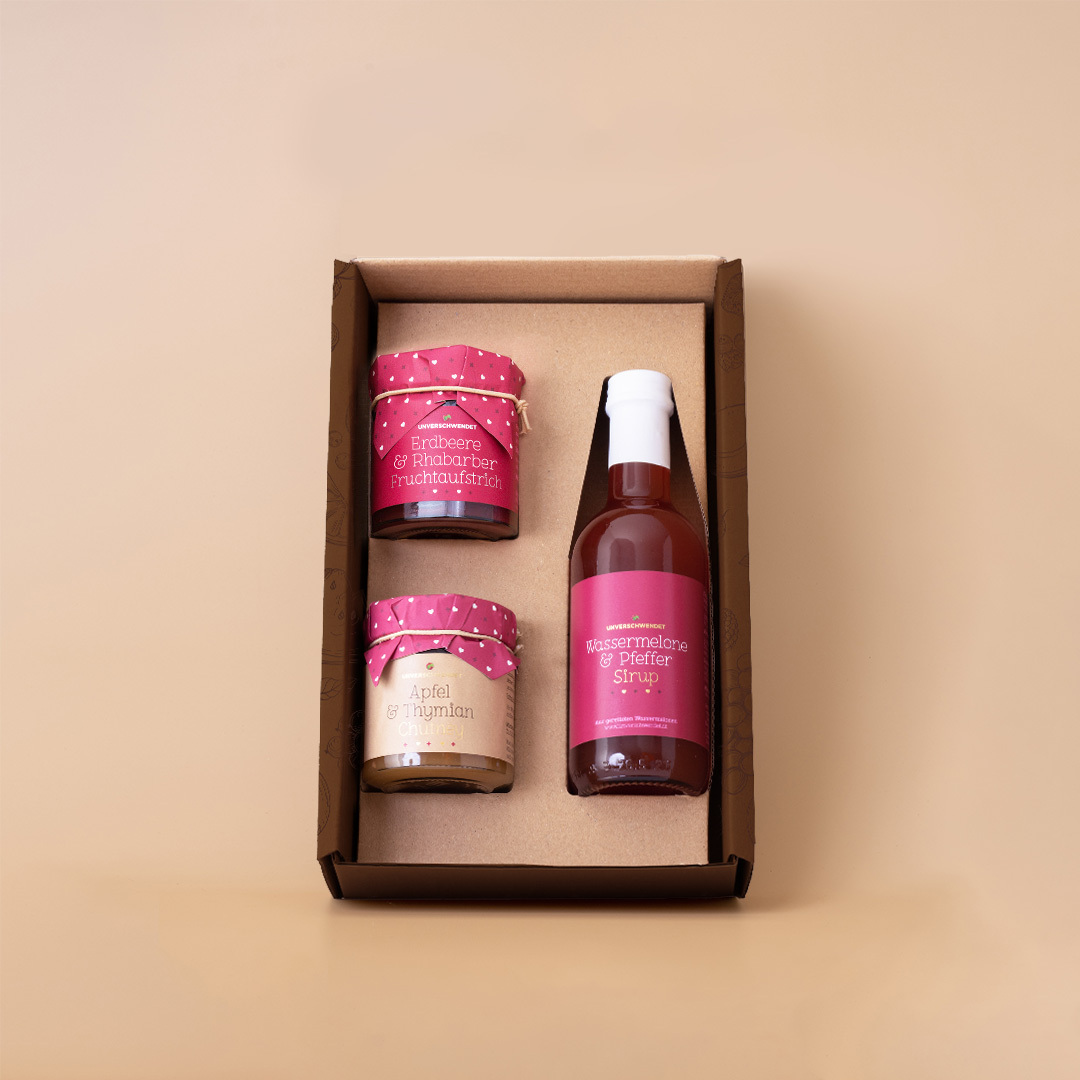 Geschenkkarton mit Apfel & Thymian Chutney, Erdbeere & Rhabarber Fruchtaufstrich und Wassermelone & Pfeffer Sirup Sicht von Oben Geschenkkarton mit Apfel & Thymian Chutney, Erdbeere & Rhabarber Fruchtaufstrich und Wassermelone & Pfeffer Sirup