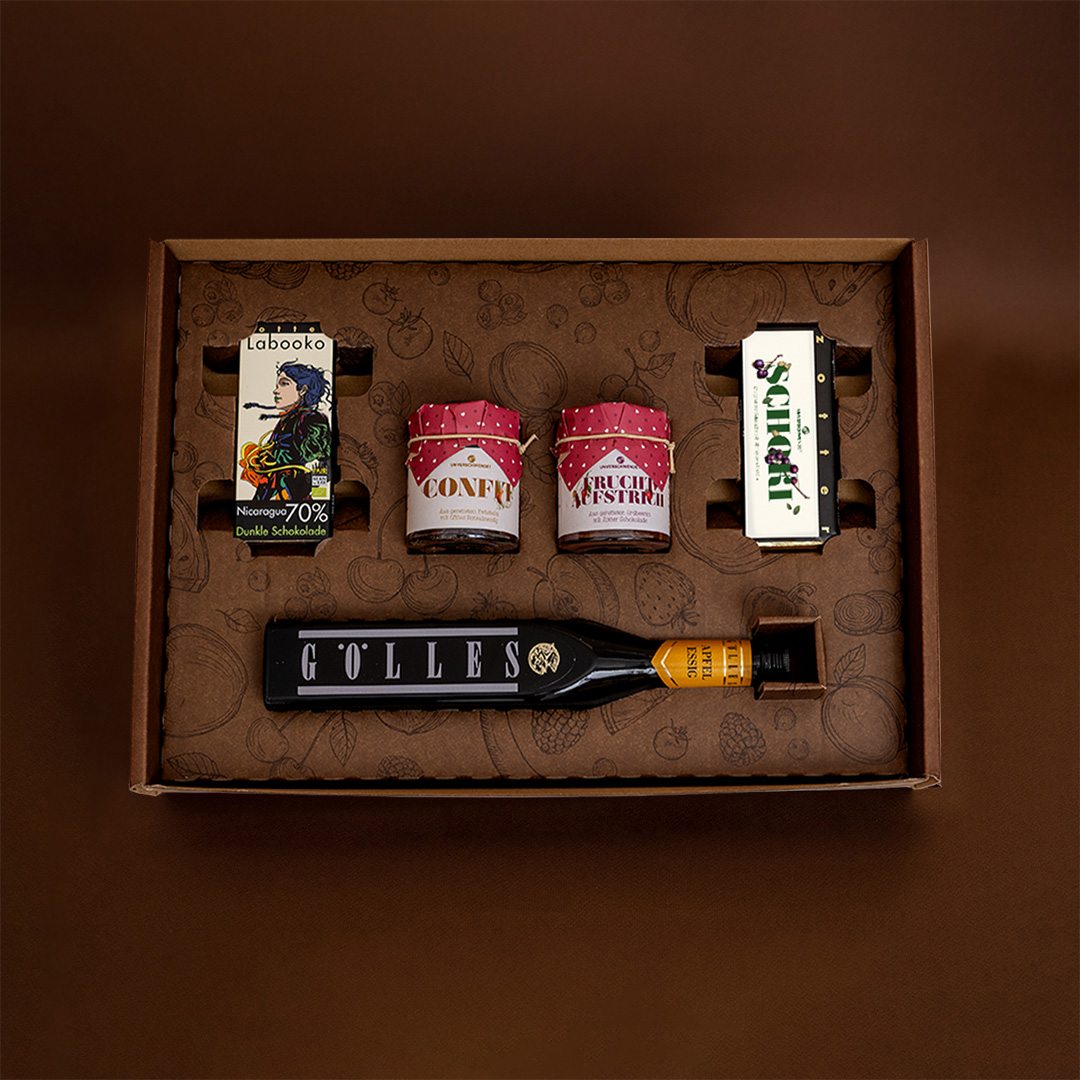 Geschenkkarton mit Schokolade. Feinkost-Gläschen und Prosecco (von oben fotografiert) Geschenkkarton mit Schokolade. Feinkost-Gläschen und Prosecco