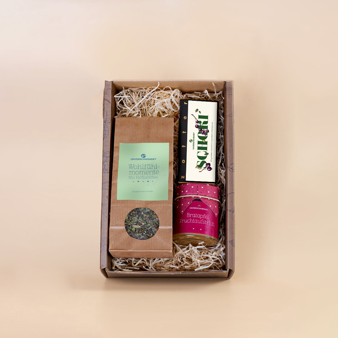 Geöffnete Geschenkbox mit Kräutertee, Schokolade und Feinkostgläschen (Vorderansicht) Geöffnete Geschenkbox mit Kräutertee, Schokolade und Feinkostgläschen